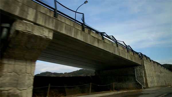 海近くの陸橋では鉄柵が波の方向に折れ曲がっています